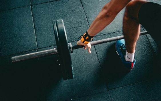 Close-up of a person lifting a barbell in an indoor gym, focusing on strength training.